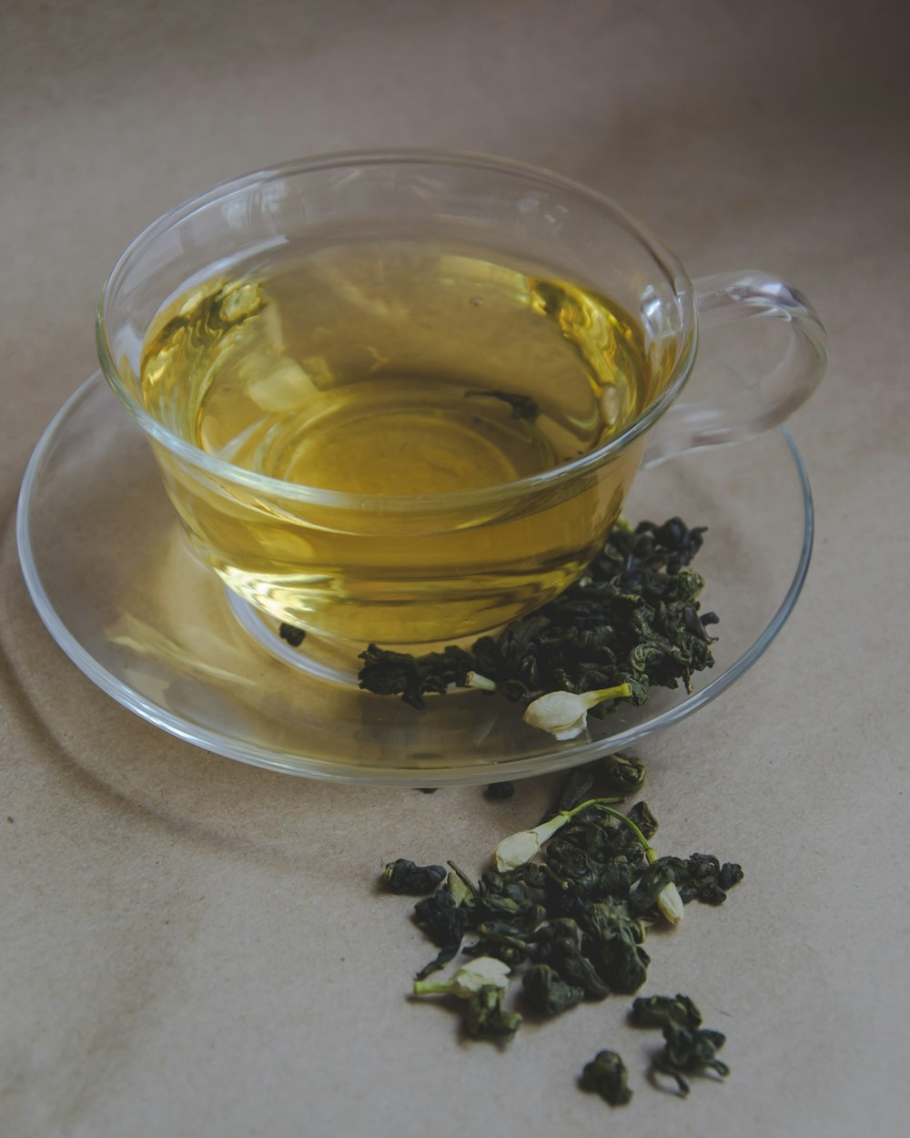 Szklana filiżanka złotego naparu oolong i zwinięte liście na spodku