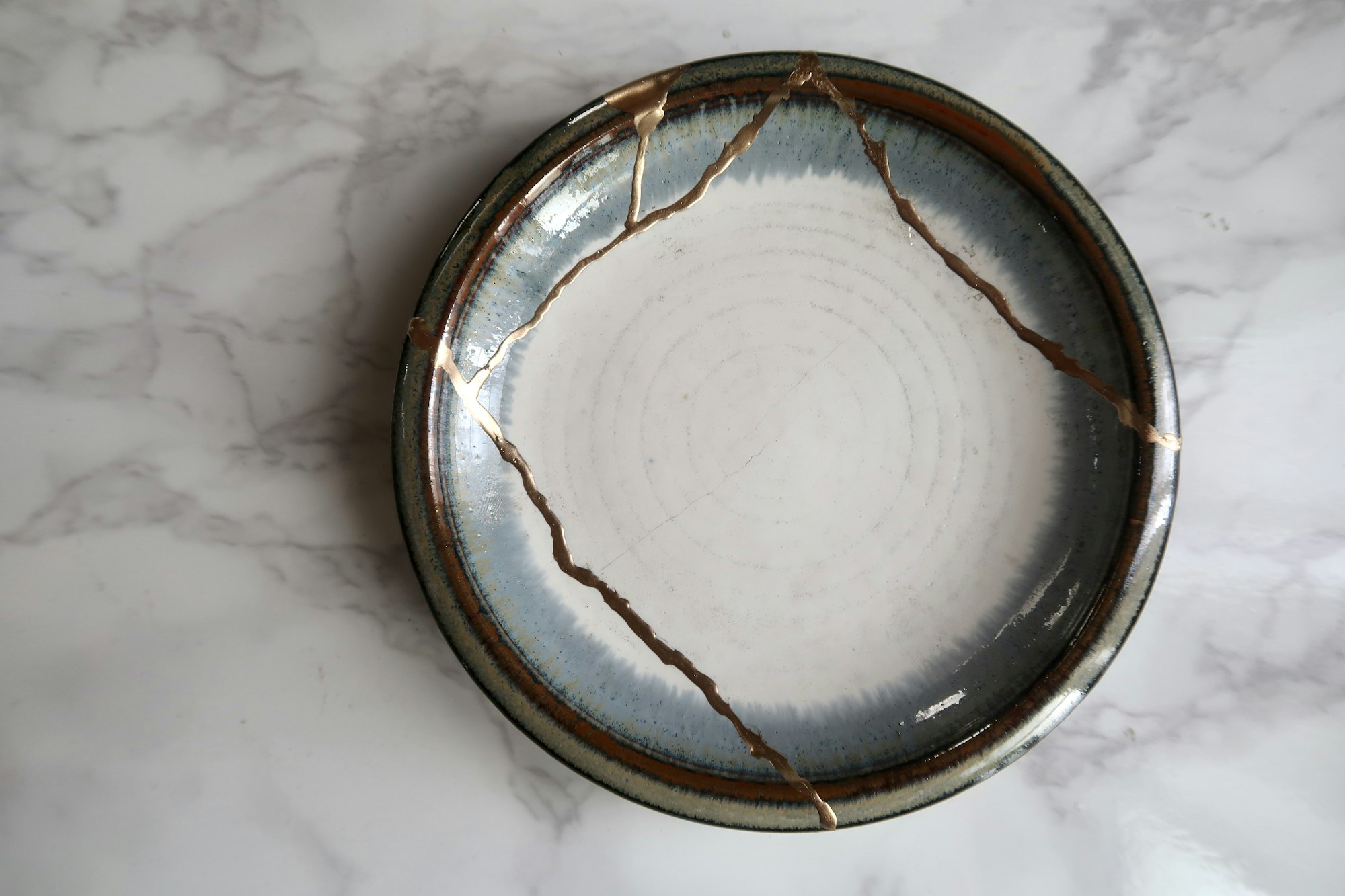 Ceramiczny talerz z pęknięciami sklejonymi złotem metodą kintsugi